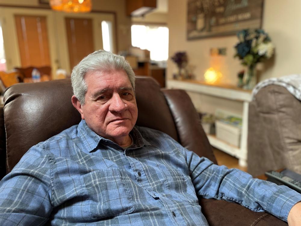 Matthew Pesce sits in an armchair in his living room