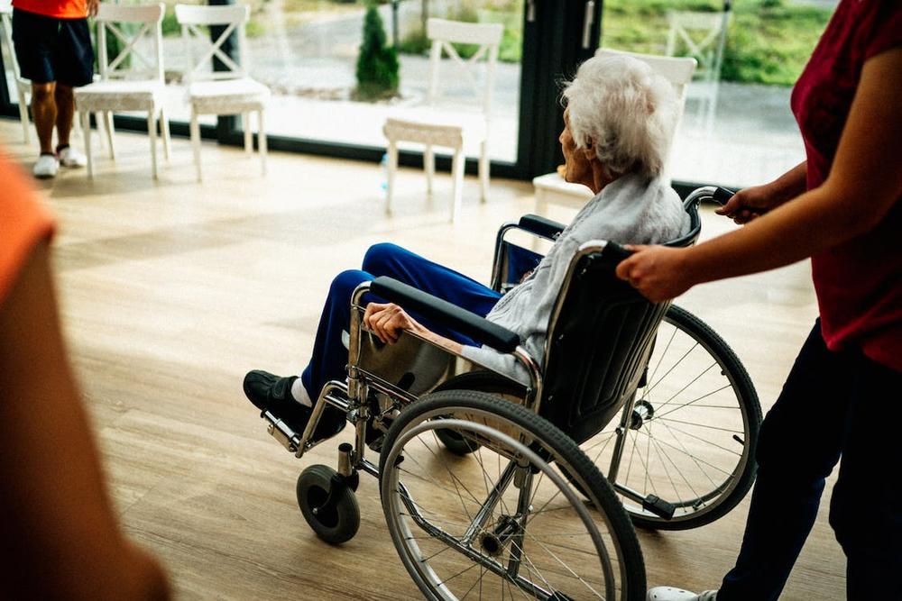 An old person being pushed in a wheelchair
