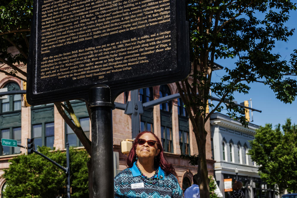 Librarian Muriel McDowell-Jackson with the historical marker about Macon's major slave market, on Poplar Street. Jackson spent eight months researching and documenting the market before penning the words of the marker.  