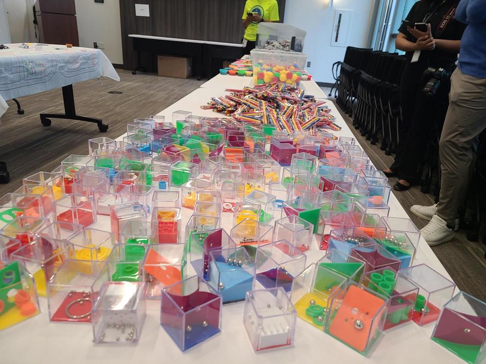 a white table full of multi colored puzzle games, crayons, and yo-yos in a conference room.