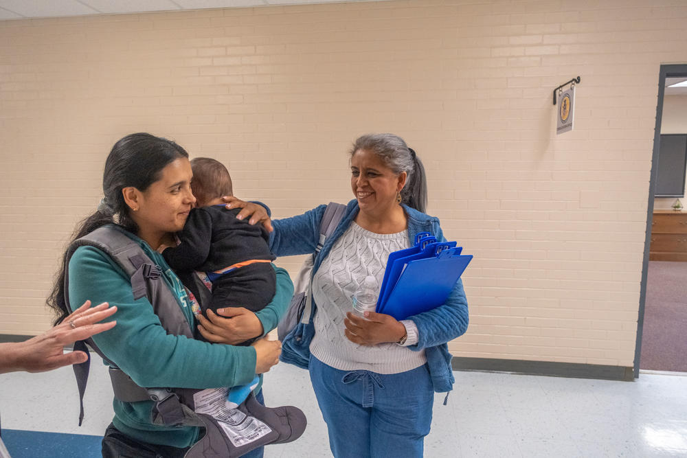 Carolina Lideno holds her baby after a brief dental exam at the pop-up clinic hosted by the Houston County School District. Each blue clip board holds information about a different screening available that day.