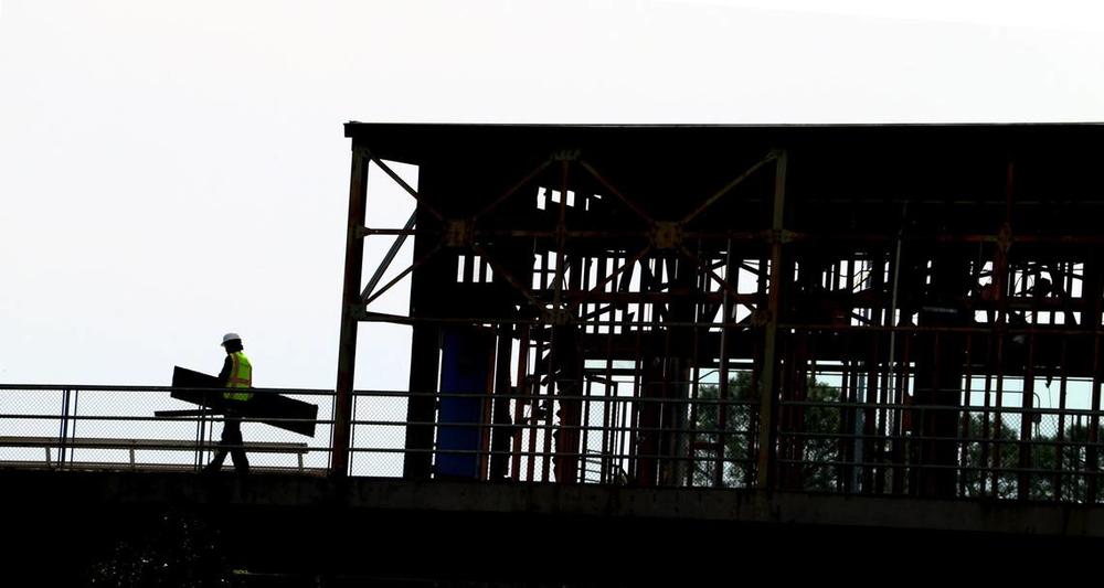 Workers carry debris to a dumpster while working on the suite level at Golden Park in Columbus, Georgia. 04/17/2024 Mike Haskey mhaskey@ledger-enquirer.com  
