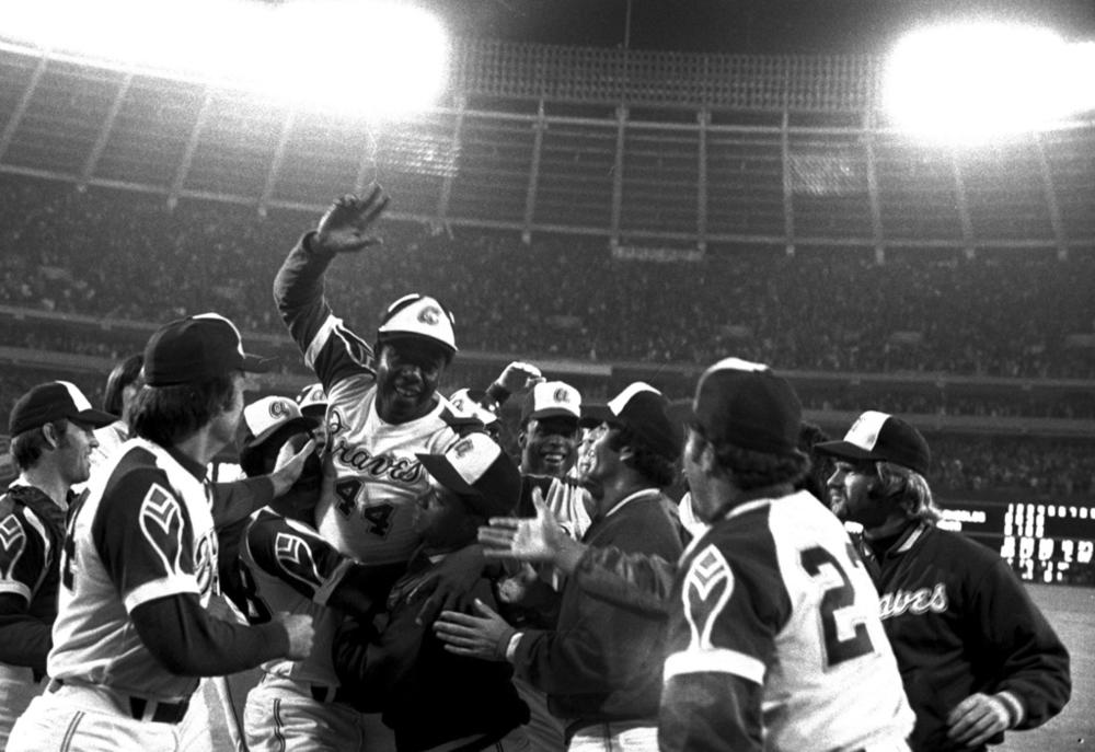 Atlanta Braves' Hank Aaron, top, is congratulated by teammates at home plate after hitting his 715th career home run in a game against the Los Angeles Dodgers in Atlanta, Monday night, April 8, 1974. Just in time for the 50-year anniversary of Hank Aaron's record 715th home run, Charlie Russo is making available video he shot of the homer.