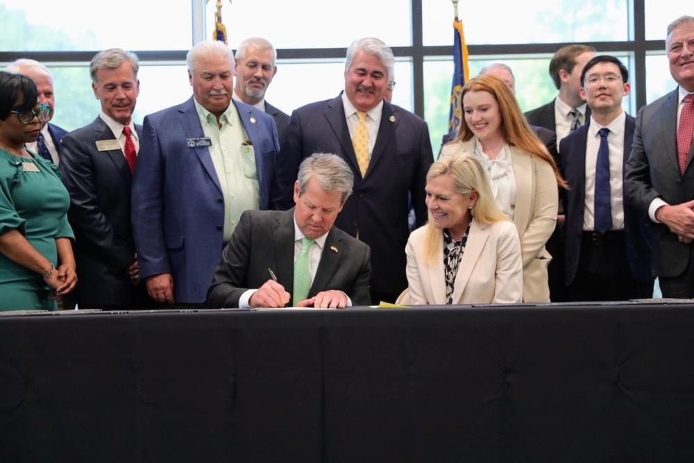 Governor Brian Kemp (left) signs several tax cut bills into law.