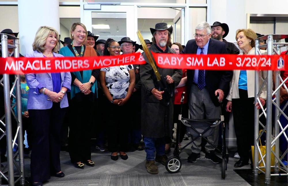 Scott Ressmeyer, co-owner of Country’s Barbecue and founder of the Miracle Ride, center, cuts the ribbon Thursday afternoon during a celebration of the new mother-baby simulation lab at Columbus State University’s School of Nursing. The lab has been named in honor of Dr. Cecil F. Whitaker, M.D., to Ressmeyer’s immediate left. Whitaker is a retired OB-GYN. 03/28/2024 Mike Haskey mhaskey@ledger-enquirer.com  