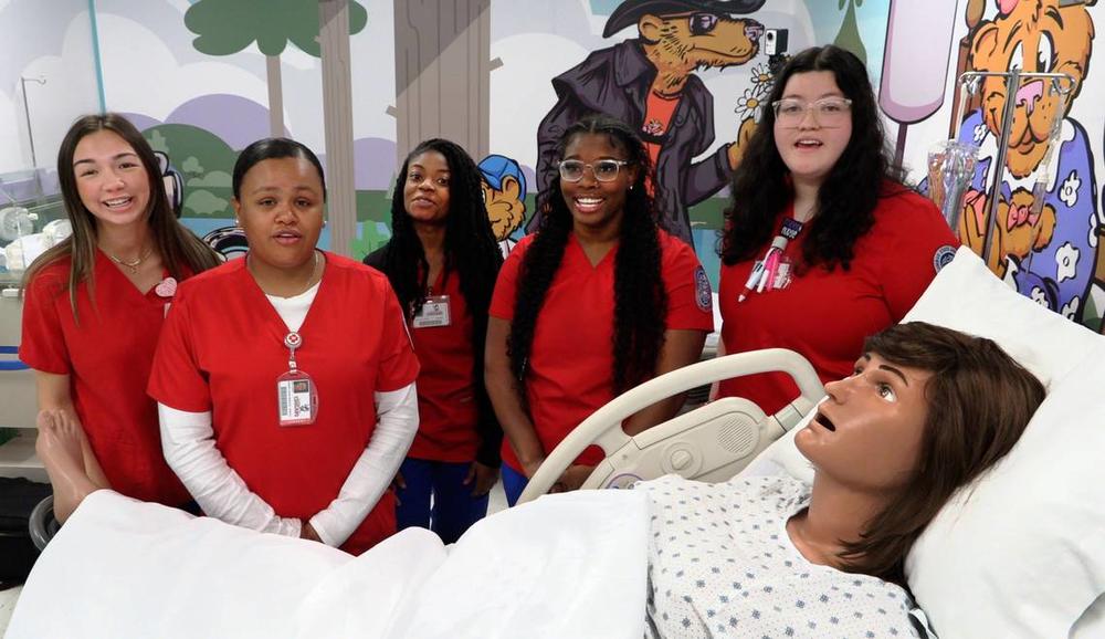 Columbus State University nursing students gather around “Victoria,” the mannequin mom that’s part of the new mother-baby simulation lab at CSU’s School of Nursing. 03/28/2024 Mike Haskey mhaskey@ledger-enquirer.com  