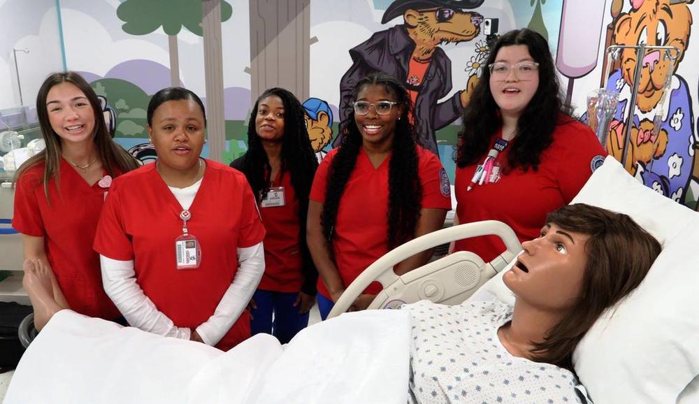 Columbus State University nursing students gather around “Victoria,” the mannequin mom that’s part of the new mother-baby simulation lab at CSU’s School of Nursing. 03/28/2024 Mike Haskey mhaskey@ledger-enquirer.com