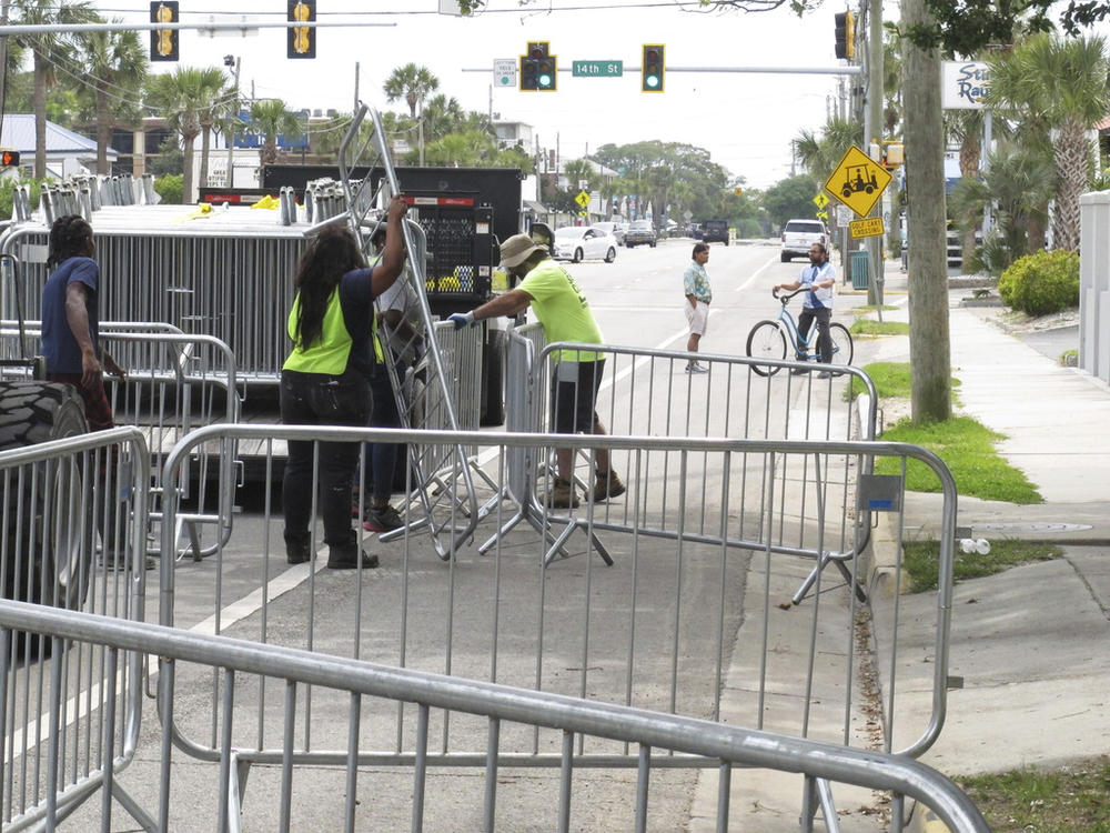 A worker places a section of metal barricade along a main road on Tybee Island, Ga., on Tuesday, April 16, 2024, a few days ahead of the weekend beach party known as Orange Crush. Black college students started the spring bash at Georgia's largest public beach more than 30 years ago. Tybee Island officials are blocking roads and parking spaces and brining in about 100 extra police officers for the party this weekend, saying record crowds last year proved unruly and dangerous.