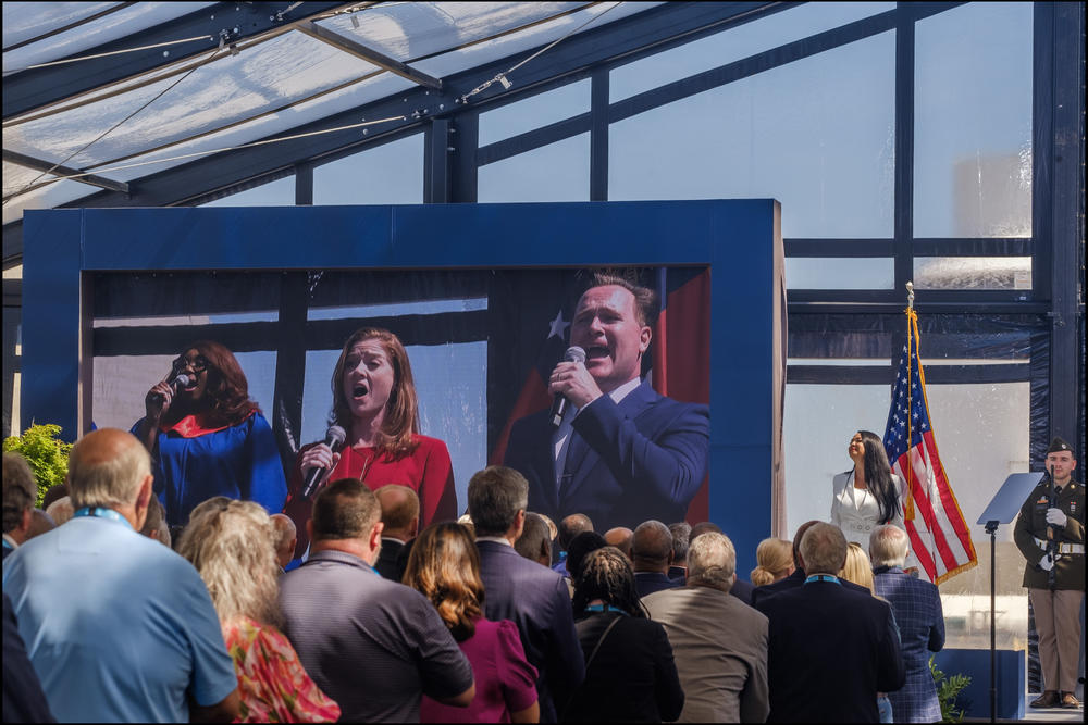 The singing of the national anthem in the air conditioned tent near units 3 and 4 at the start of the celebration Wednesday. 