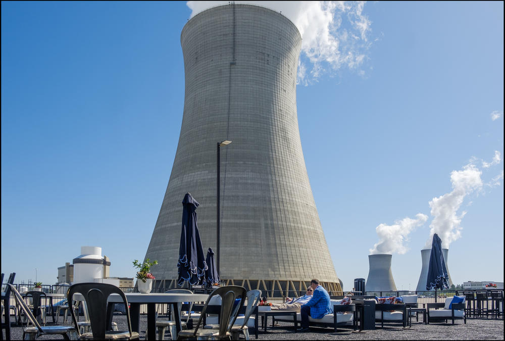 A temporary patio set up for the day in the shadow of one of the new units, left, and its cooling tower. 