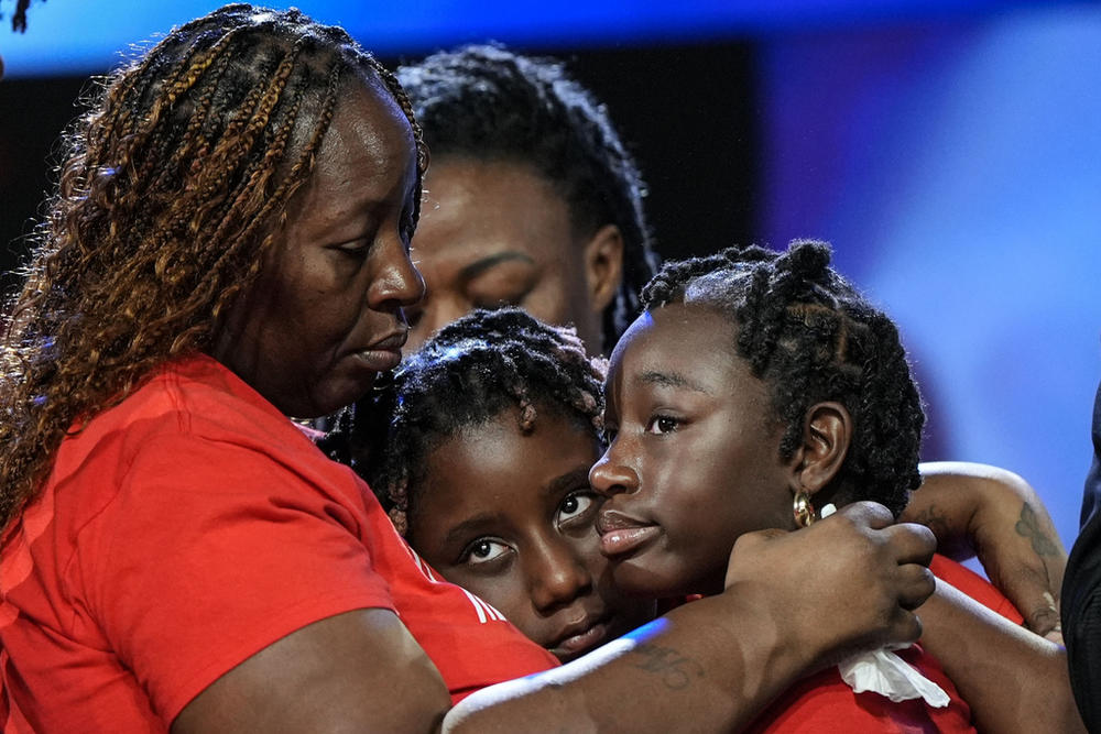 Four people, including Chantemekki Fortson, are shown in an embrace.