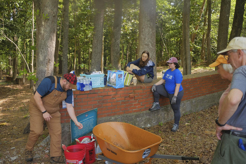 After the rediscovery of the Penfield African American Cemetery, a gap was knocked in the brick wall to allow access by local stakeholders and volunteers like these who work to push back enough of the forest in the space that they can begin to understand it.