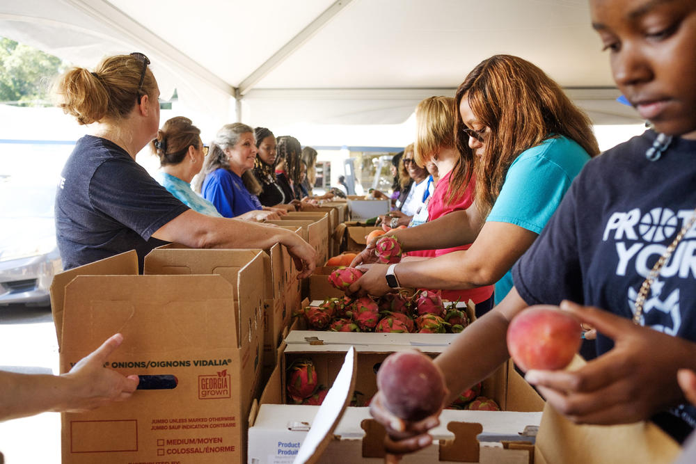 Volunteers pack boxes assembly-line style during the annual food distribution in Macon sponsored by Atrium Health. About 60 tons of fresh produce was packed and distributed on a first come, first served basis at the three hour event Friday for which some people arrived two hours early.
