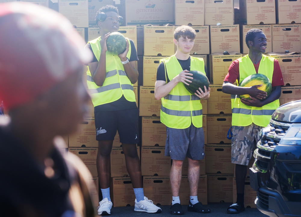 Members of the cross country team from Macon’s Howard High School waiting to deliver, on request, a watermelon to a waiting car. 