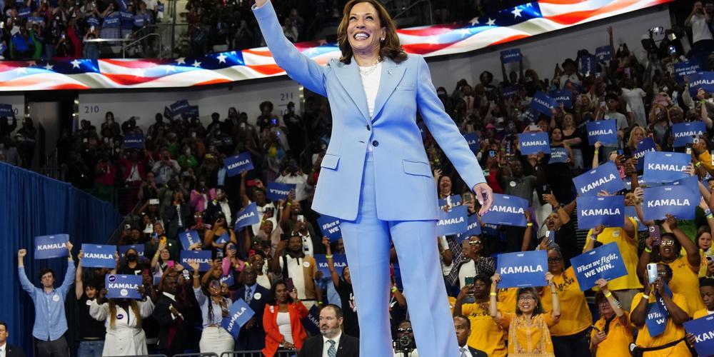 Kamala Harris is shown waving to a large crowd.
