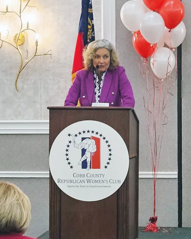 Pamela Reardon is shown speaking at a podium that has a Republican logo and says "Cobb County Republican Women's Club."