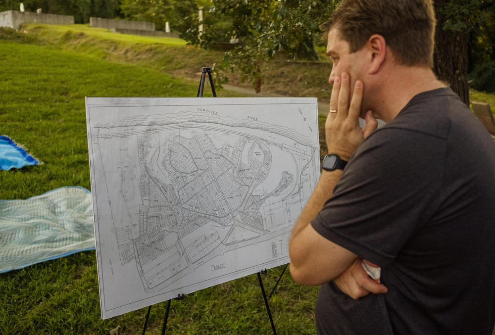 A man examines a 1954 map of the Oak Ridge cemetery and the larger Rose Hill/Riverside Cemetery complex shows almost none of the Oak Ridge burials. An 1879 maps described dozens. 