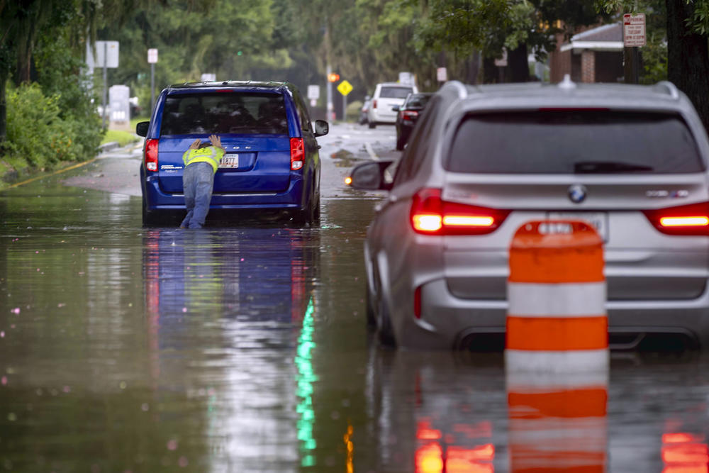 The driver of a stranded vehicle pushes his van out of a flooded street after heavy rain from Tropical Storm Debby, Monday, Aug. 5, 2024, in Savannah, Ga.