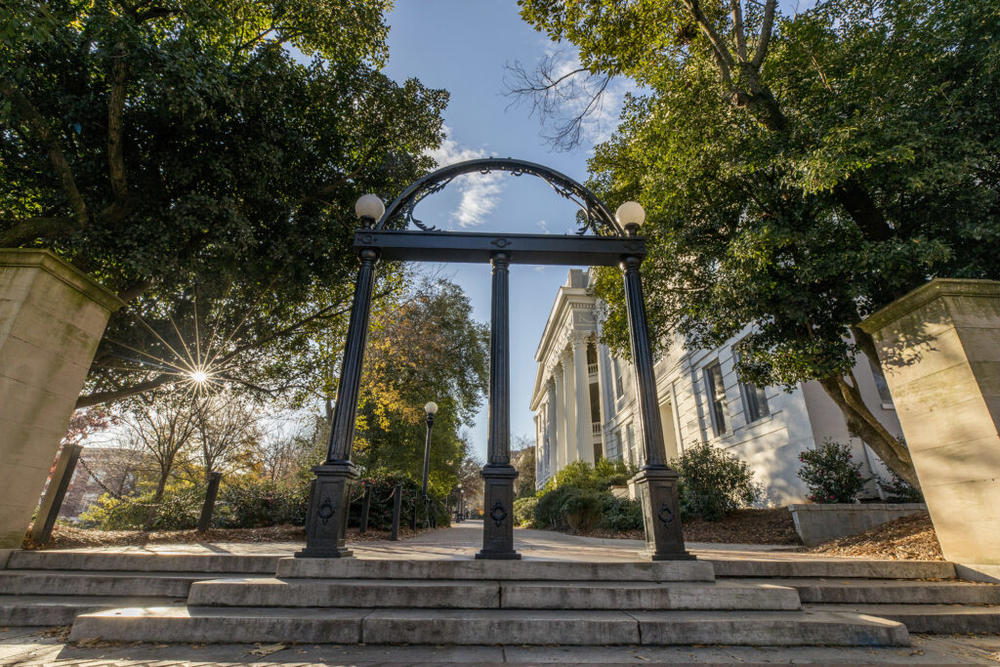 The University of Georgia arch is shown with the sun from behind.