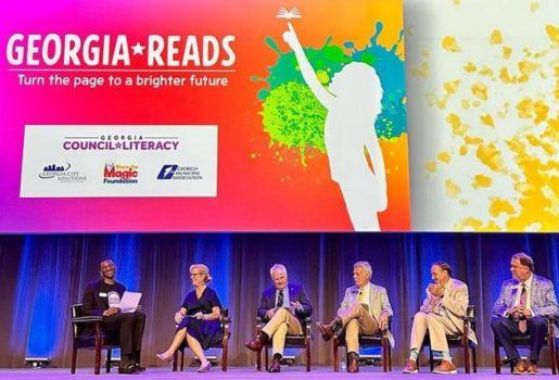 Malcolm Mitchell presents his book onstage, to the left of five additional speakers.