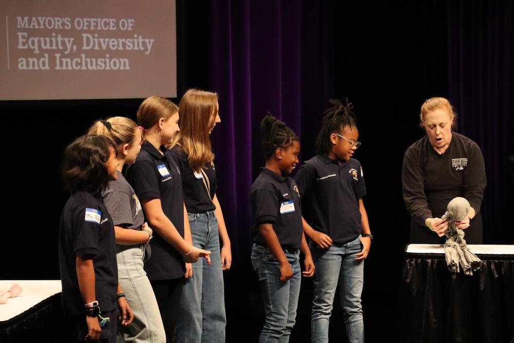 Reay Kaplan Maxwell, manager of the Center for Puppetry Arts education initiatives, walks young girls through a mental well-being puppet exercise at the City of Atlanta’s International Day of the Girl celebration. Ambria Burton/GPB News