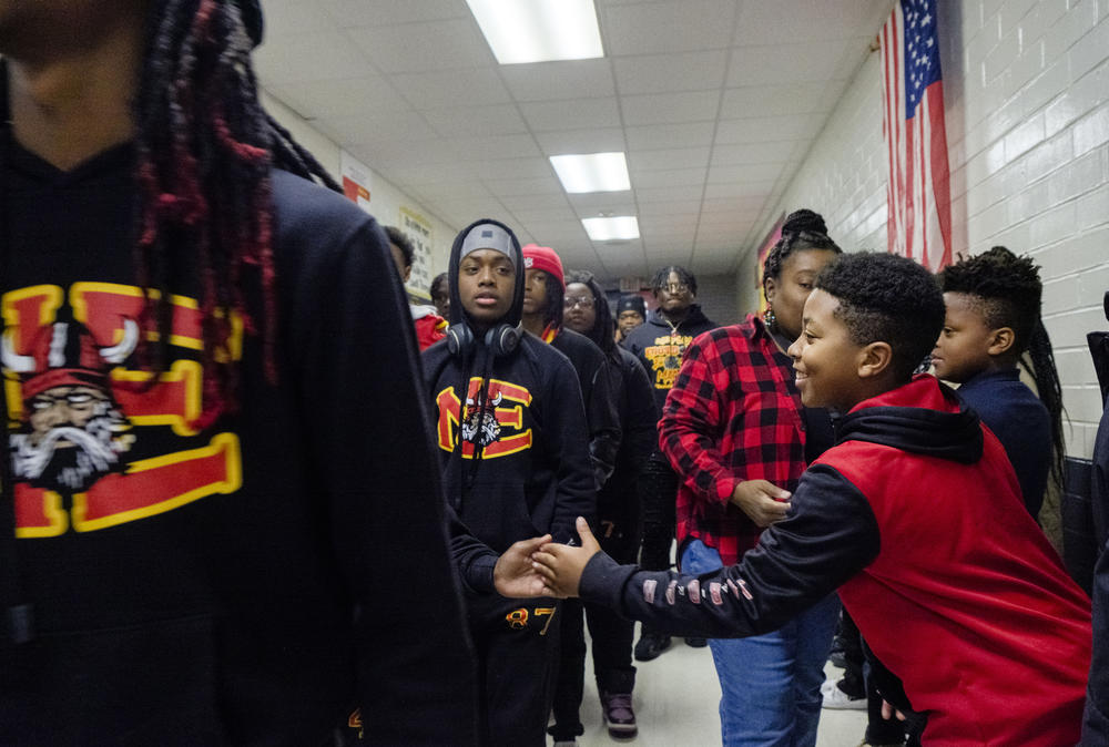 RJ Veal, a right, a fourth grader at Macon's Bernd Elementary School gives five to a member of Macon's Northeast High School Raiders football team at the start of the team's tour of all the schools feeding Northeast High Monday. The team made the trip ahead of their GHSA championship game against Toombs County. 