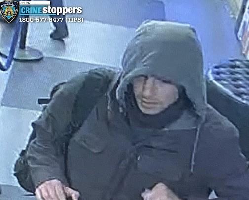 A grainy surveillance video image shows a person wearing heavy grey coat.  The person's face is partially obscured by the coat's hood.