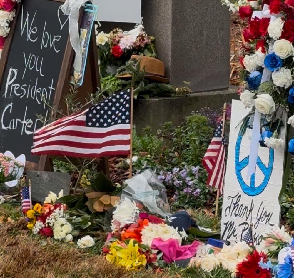 A memorial at the entrance of the Carter Center is covered in flowers, flags and notes from those who are remembering the life and legacy of former President Jimmy Carter, who died on Dec. 29, 2024.