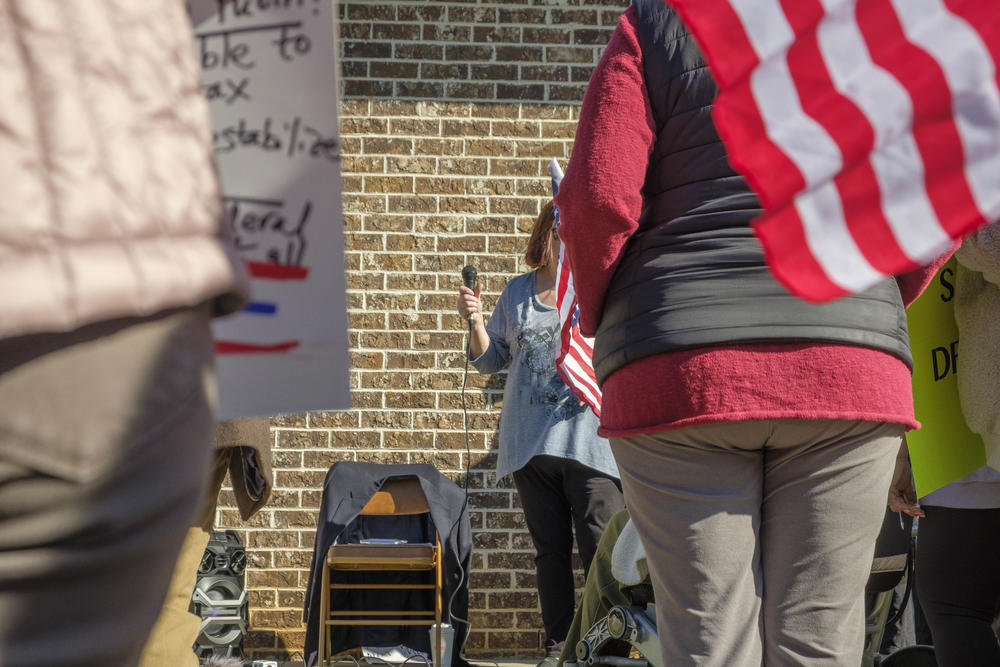 Since Representative Austin Scott was not at his Warner Robins district office, the nearly people who gathered there Monday put their questions to an empty chair draped with a blue blazer instead.