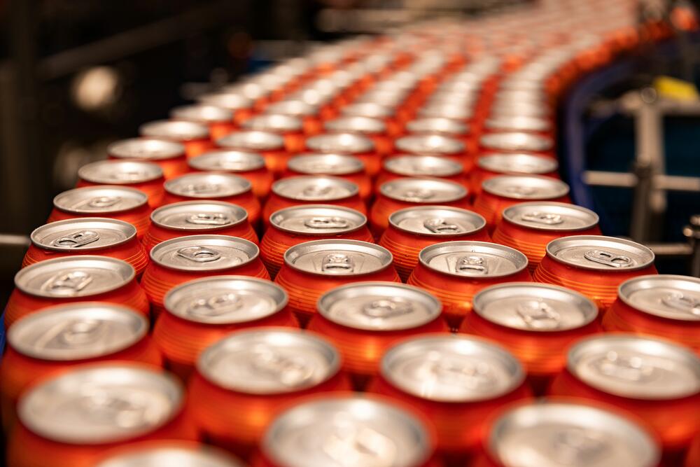 Cans in rows on a conveyor belt at a production facility.