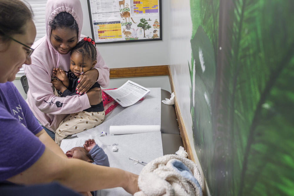 Mahogany Brown, top left, watches with her daughter Mahailley as Mahogany’s infant son Memphis Exum receives one of a number of vaccinations during a routine visit to pediatrician Brittany Lord in the town of Eastman recently.