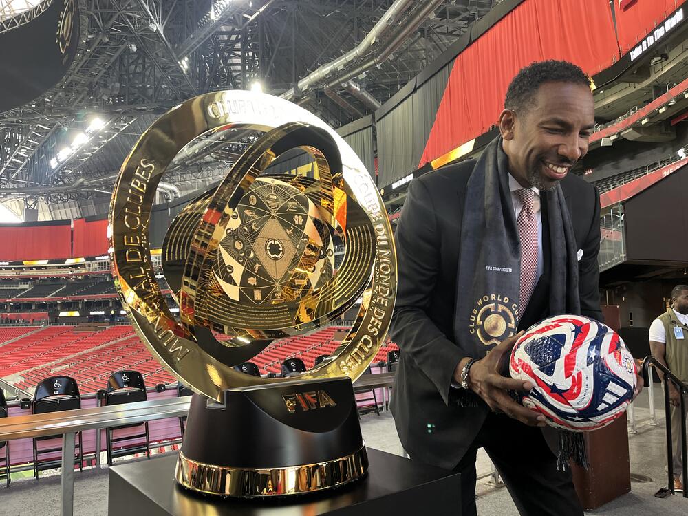 Mayor Andre Dickens poses next to the 2025 Club World Cup trophy with a soccer ball.