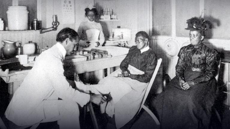 A black and white photo of people in a doctor's office.
