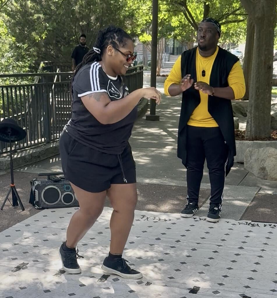 Anthony "Fyrefli" Gasaway Jr (back row, third from left) and Joy "Kuma" Gasaway (seated, holding boombox) gather with FyreNation Crew members and cypher participants at Atlanta's Old Fourth Ward Park on April 27, 2025.