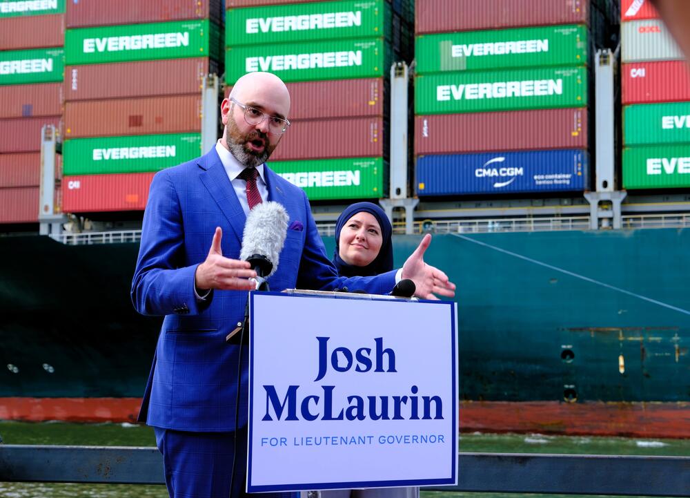 Georgia Sen. Josh McLaurin of Atlanta, standing next to Georgia Rep. Ruwa Romman of Duluth, announces his run for lieutenant governor along downtown Savannah's riverfront on Monday, May 5, as a container ship sails toward the Port of Savannah.