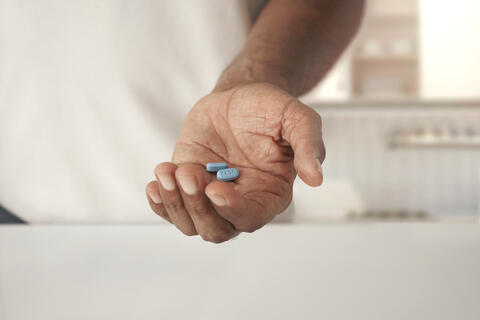 A hand holding two blue pills