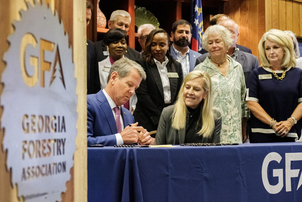 Georgia Governor Brian Kemp, with his wife Marty, center, signs bills related to hurricane relief for farmers and timber growers at the Monroe County headquarters of the Georgia Forestry Association Thursday.