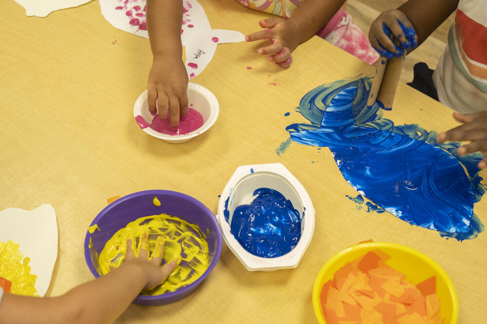 Toddlers play with paint at the Child Development Center.