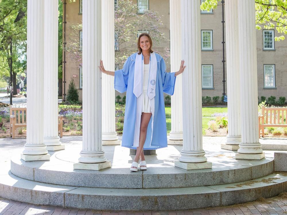 Ruth McCrady stands outside in a blue graduation robe