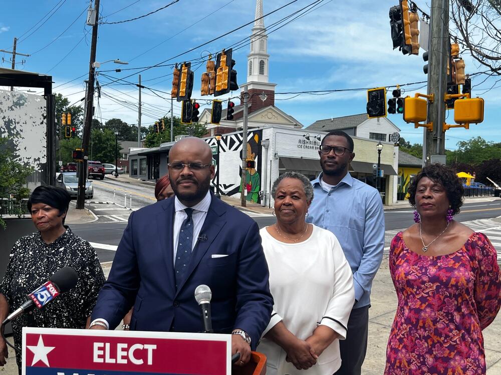 Wayne Martin stands behind a podium with older people from the community.