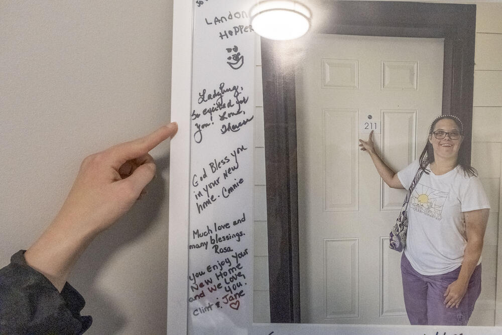 Bethany Beech points to messages written by friends and family along the sides of a framed photo of her taken upon the construction of her apartment in the Soaring Heights community of Conyers.
