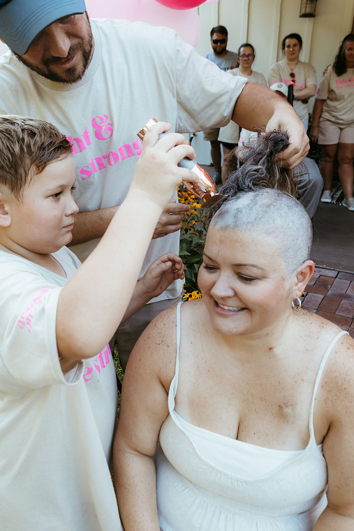 A man and a boy shave a woman's head