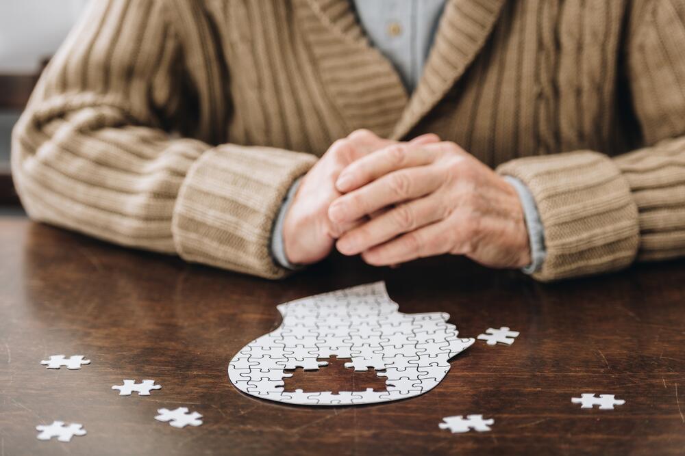 senior man playing with puzzles on table
