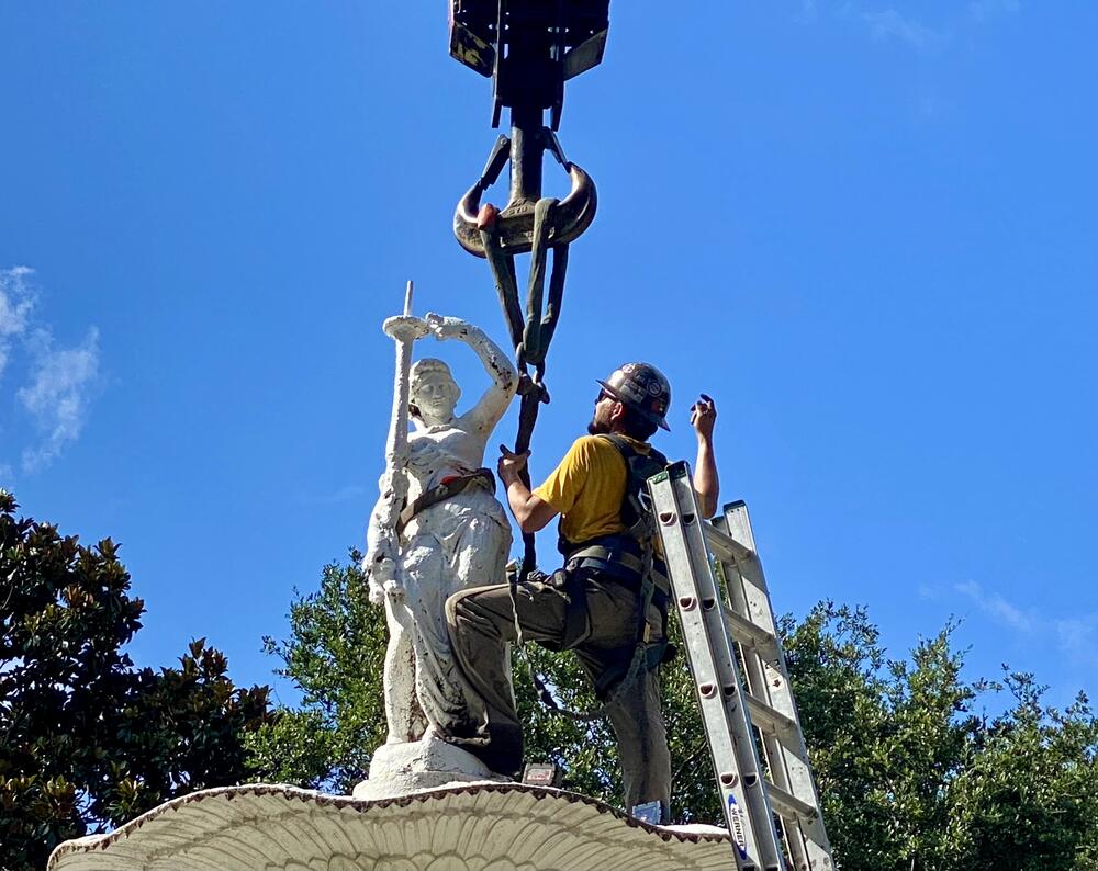 A worker attaches the Forsyth Park fountain's crowning statue onto a crane for removal on Monday, June 23.