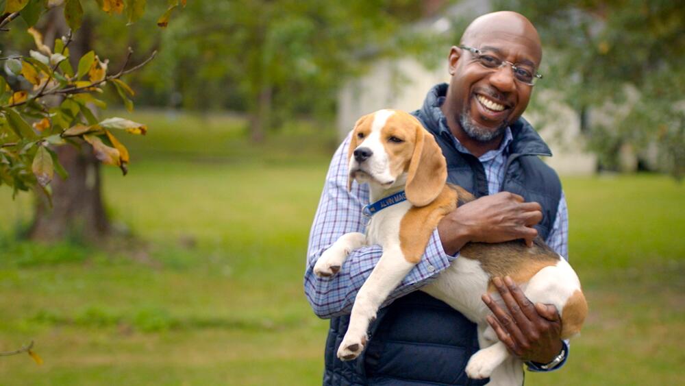 Raphael Warnock holds a beagle in a 2020 campaign photo.