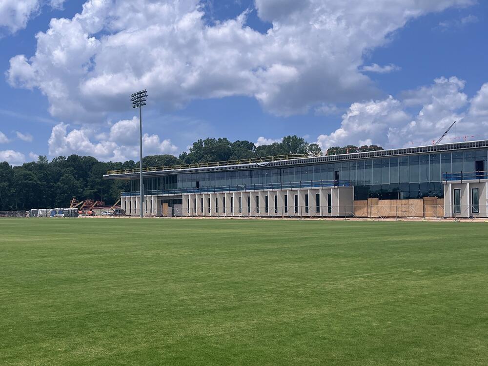 A large grass field next two a large building with glass windows