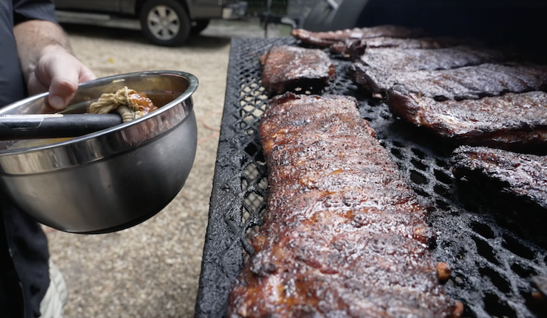 Someone basting a rack of ribs.