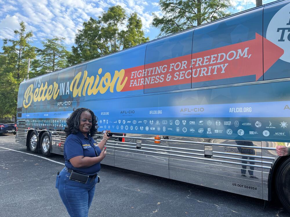 A woman in a navy shirt stands in front of the AFL-CIO "It's Better in a Union" tour bus on July 22, 2025.