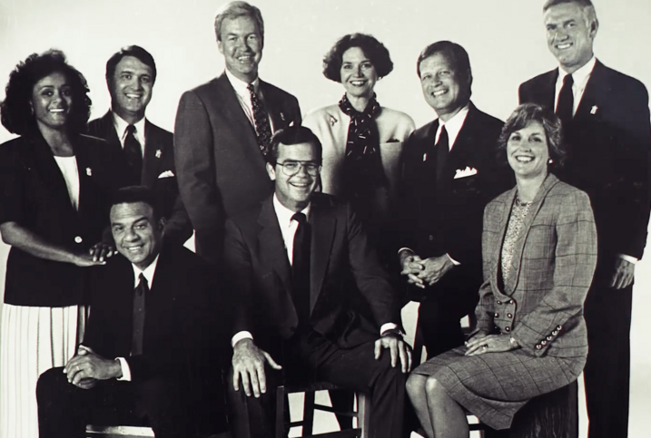 A black and white photo of nine people posing.