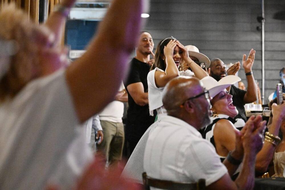 Her Majesty Kitchen owner Chelsia Green Ogletree holds her hands on her head after the announcement of her winning Food Network competition show “Chopped” while watch party attendees react on Tuesday, July 8, 2025, at Her Majesty Kitchen in Forsyth, Georgia. Ogletree won the competition out of four chefs from across the country and a $10,000 prize.